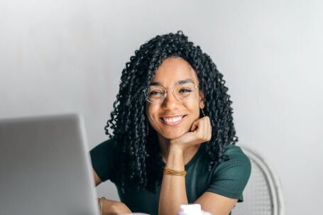 Online Reputation - Happy ethnic woman sitting at table with laptop